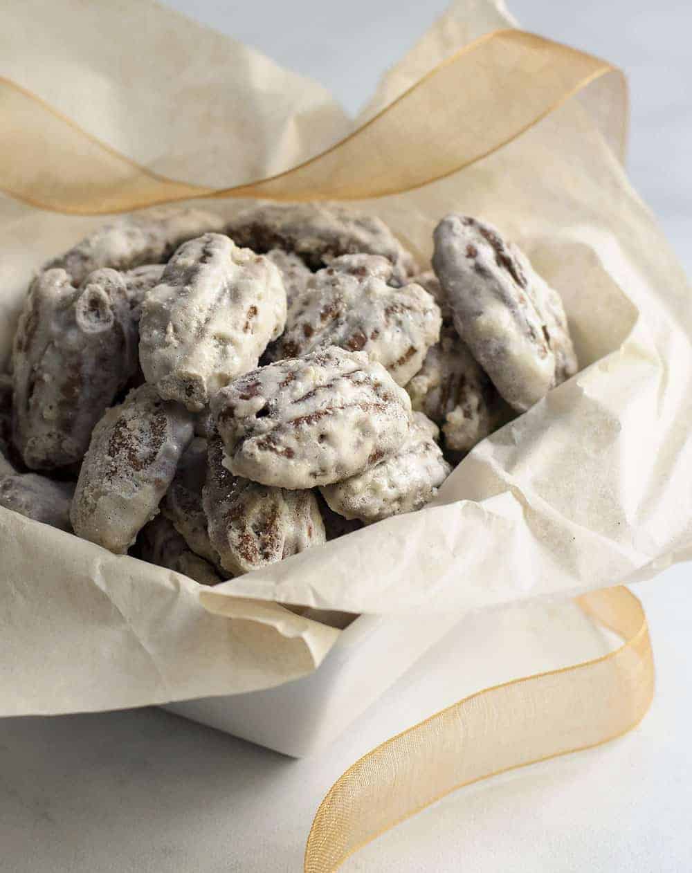 Sugared Pecans in a white square bowl with tissue and ribbon