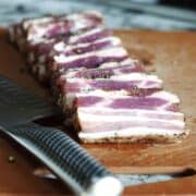 Homemade Pancetta sliced on a cutting board