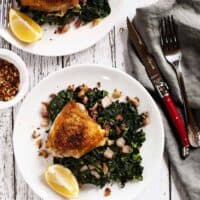 Crispy-Chicken-Thighs-with-Kale-and-Bacon on white plates