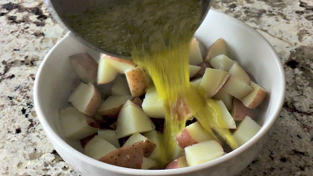 Pouring Olive Oil Mixture Over Tender Steamed Potatoes