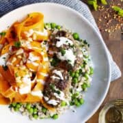 Lamb Kofta served with carrot salad and barley with peas in a white bowl