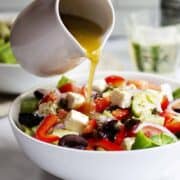 Greek Salad Dressing pouring from a white pitcher