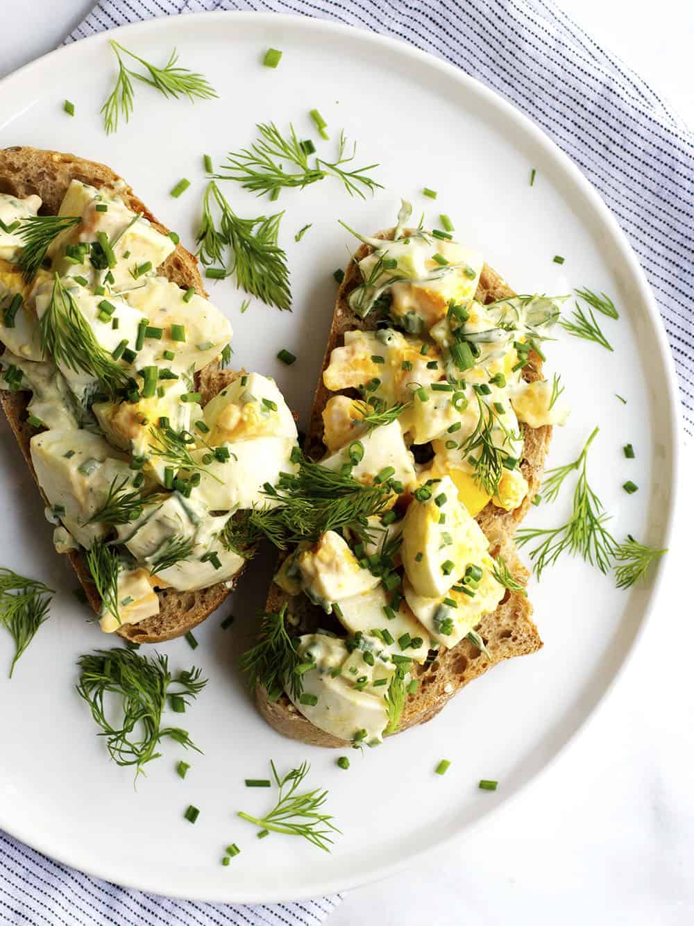 egg salad served open faced on a white plate
