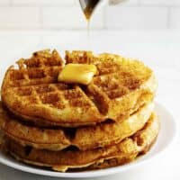 pouring syrup over a stack of Belgian Waffles