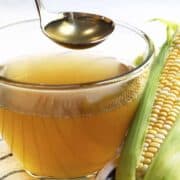 corn stock in a bowl and ladle with whole ear of corn beside and cloth napkin under