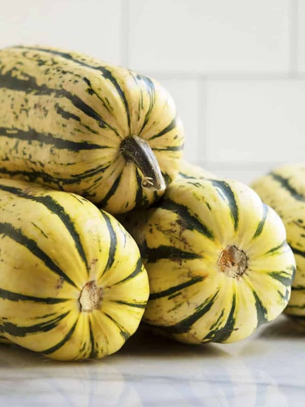 Delicata Squashes stacked on a marble board