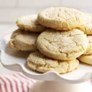 Almond Flour Sugar Cookies stacked on a white cake plate