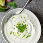 Cilantro Lime Crema served in a white bowl with a silver spoon.
