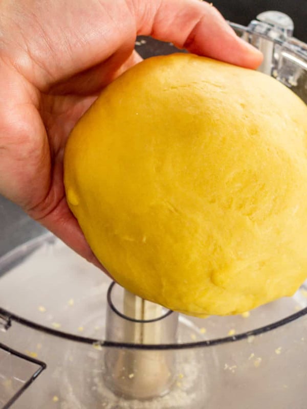 fresh pasta dough ball held above the food processor bowl