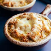 Vegetarian French Onion Soup served in traditional brown bowls with a long handle