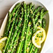 Lemon Garlic Asparagus served with lemon slices on an oval ceramic platter