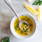 Lemon Garlic Butter Sauce served in a white bowl with a serving spoon on a white marble board