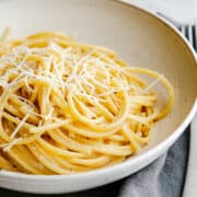 Bucatini Cacio e Pepe served in an ivory ceramic bowl.