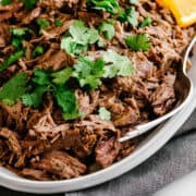 shredded lamb barbacoa served on an oval platter.