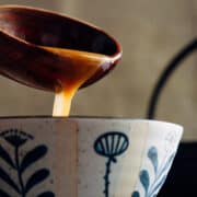 ladling miso ramen broth into a Japanese bowl.