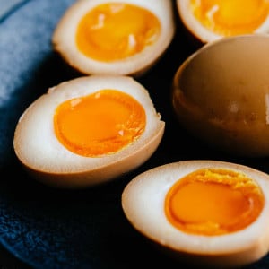 soy sauce eggs sliced in half on a black plate.