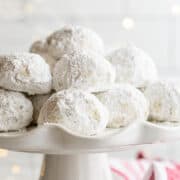 Italian wedding cookies stacked on a white ceramic cake stand.