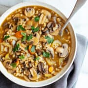 Mushroom Barley Soup served in a light gray ceramic bowl photographed from above.