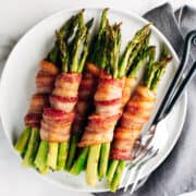 bacon wrapped asparagus served on a round white platter and photographed from above.