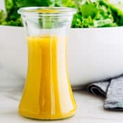French Vinaigrette served in a small carafe with a green salad behind.
