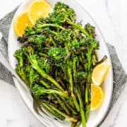 grilled broccolini on a white oval platter photographed from above.