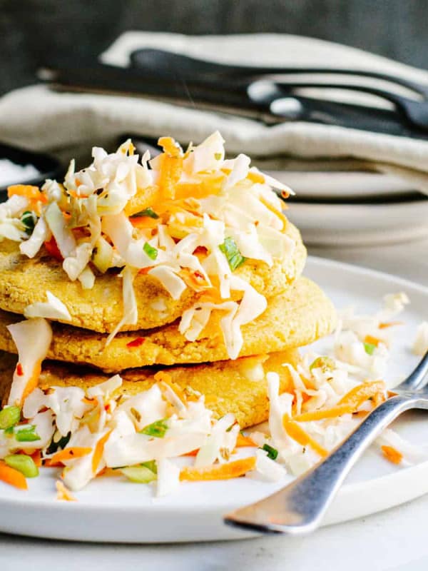 Pupusas stacked on a white plate with curtido.