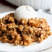 Apple Crisp served on a white plate with a scoop of vanilla ice cream.