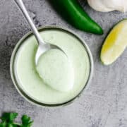 Spooning jalapeno Ranch Dressing out of a glass jar.