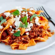 Lamb Ragu with pasta on a white plate.