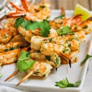 Spicy Grilled Shrimp served on a white platter with lime wedges.