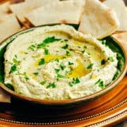 White Bean Hummus served in a green ceramic bowl with pita bread for dipping.