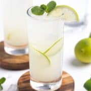 Close up of Virgin Mojito served in a tall glass garnished with lime wheels and mint.