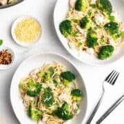 Chicken Broccoli Pasta served in oblong white bowls on a white marble surface and photographed from overhead.