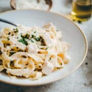 Garlic Parmesan Chicken Pasta served in a white ceramic bowl photographed at an angle.