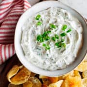 Green Onion Dip served in a white ceramic bowl with potato chips and photographed from the top.