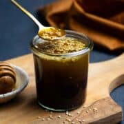 Sesame Ginger Dressing served in a small glass jar with a golden spoon.