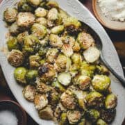 Close up shot of Garlic Parmesan Brussels Sprouts served on a white oval platter and photographed from the top.