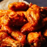 Crispy Baked Buffalo Wings served on parchment paper on a platter.