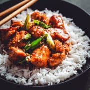 Mongolian Chicken served in a wide black bowl with chopsticks and photographed at an angle.