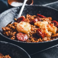 Jambalaya served in a black ceramic bowl and photographed at an angle.