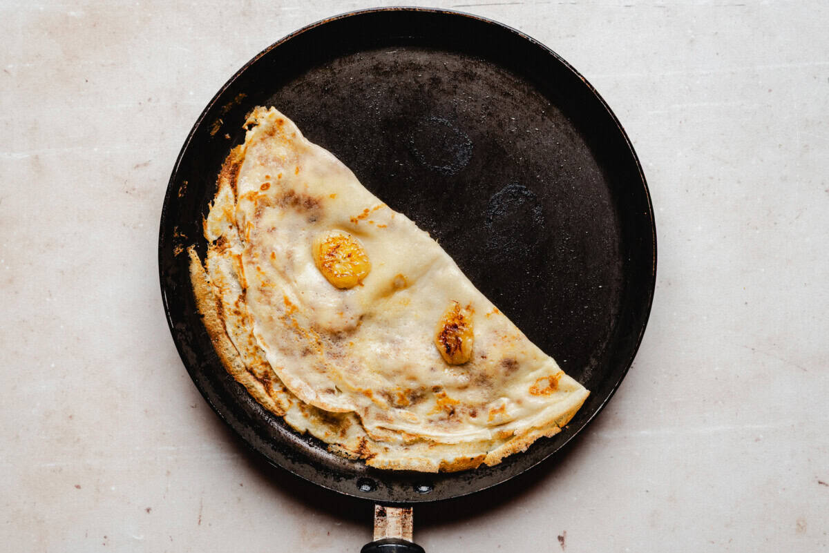Banana crepes filled with caramelized banana slices, folded in half on a light surface.