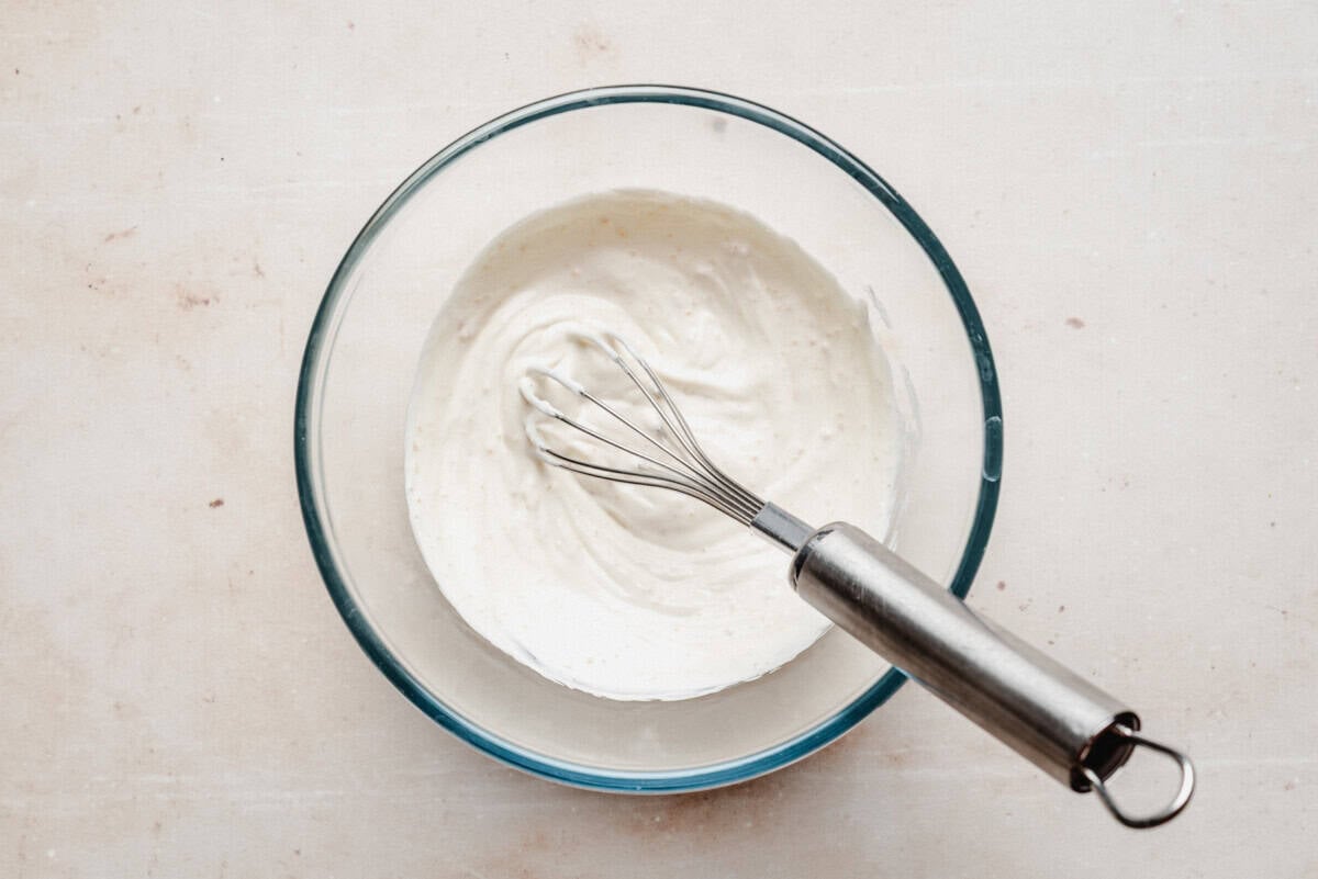 sour cream and sugar in a glass bowl, thick and creamy with smooth white texture.