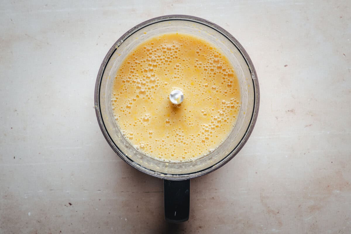A top-down view of a blender cup filled with blended corn shrimp and broth, sitting on a light-colored surface.